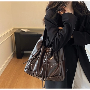 Detail view of large dark brown leather bucket bag with silver studs on a model