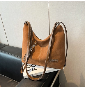 Detail of vintage brown suede tote bag with contrast stitching and branded leather patch