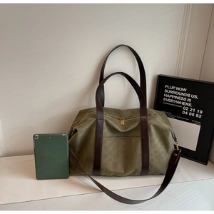 Detail of olive green canvas tote bag with brown leather straps and metal zipper