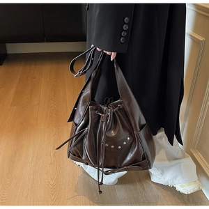 Detail view of deep coffee vintage bucket bag with silver rivet studs and drawstring closure