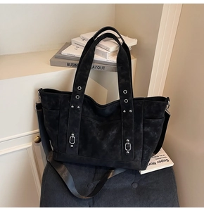 Detail of black canvas tote bag showing metal eyelet buckle and adjustable strap texture