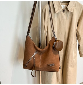 Detailed view of brown matte leather tote bag with decorative zipper and small round pouch