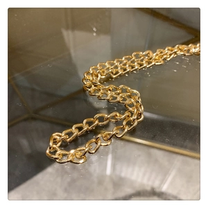 Detail of elegant gold metal chain strap on vintage cheongsam handbag with high polish finish