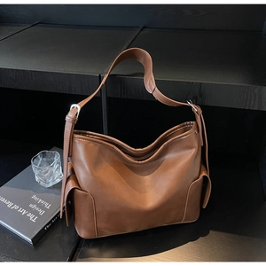 Detail of dark brown leather hobo bag with side pockets and adjustable strap on black stand