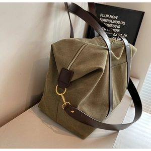 Close-up of olive green canvas travel tote with brown leather handles and gold hardware