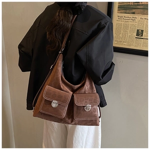 Detail of vintage brown suede tote with dual front flap pockets and silver metal buckles