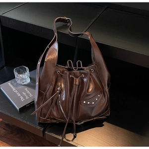 Detail of dark brown vintage bucket bag with silver rivets and polished leather texture