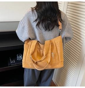 Detailed back view of a mustard yellow canvas tote bag with side pocket and silver rings