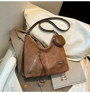 Detail of caramel suede hobo bag with metal zipper and round coin purse charm