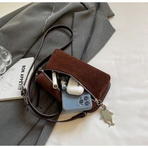Internal capacity of brown suede crossbody bag with phone, lipstick and robot charm