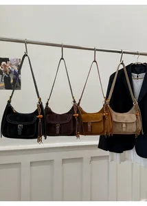 Detail view of the retro suede hobo bag with tassel charms and four classic color options