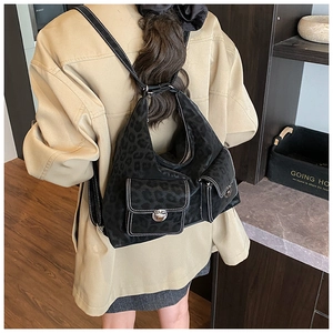 Detail view of black leopard print backpack with white contrast stitching and metal buckles