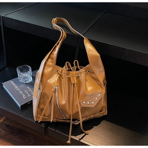 Detail view of brown leather bucket bag with silver studs and zipper on display