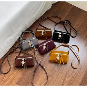 Close-up of suede crossbody bags with cute metal robot pendants and tassel details