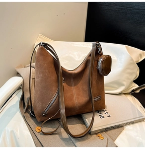 Detail view of brown suede tote bag with contrast stitching and small round coin purse