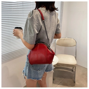Detail view of a vintage red shell bag with metal clasp and chain strap on a model