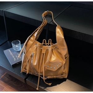 Detail of caramel brown faux leather bucket bag showing rivet pocket and texture