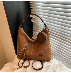 Close-up of brown frosted leather tote bag detail with round zipper pouch and logo label