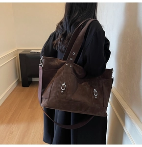 Detail showing deep brown suede tote bag texture with silver rings on model shoulder