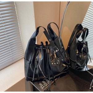 Detail of black glossy leather bucket bag featuring silver studs and drawstring closure