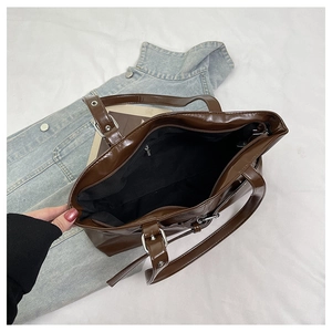 Detail view of large brown tote bag interior with zipper pocket and metal buckle strap