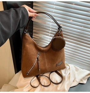 Detail of dark brown suede tote bag with contrast stitching and small coin purse attachment