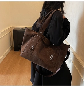 Detail view of large brown vintage tote bag with rivets and adjustable shoulder strap