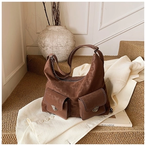 Detail of vintage brown suede shoulder bag with dual front pockets and contrast stitching