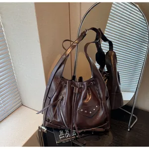 Detail of dark brown oil wax leather bucket bag with stud accents and drawstring