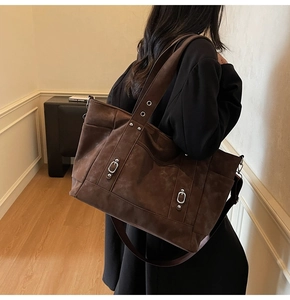 Detail of vintage brown canvas tote bag with long shoulder straps and metallic buckle