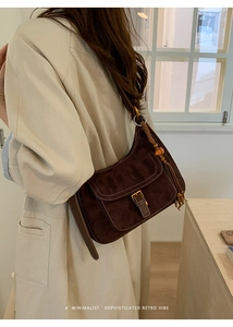 Detail view of a vintage dark brown suede underarm bag with decorative tassel and metal clasp