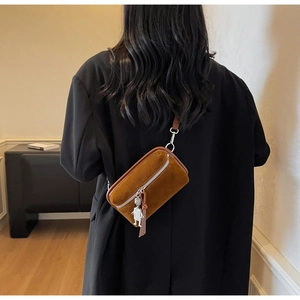 Brown faux suede crossbody bag with silver robot charm shown on model in black blazer