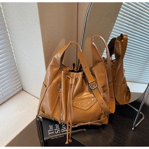 Macro detail of brown PU leather bucket bag with silver studs and decorative side zippers