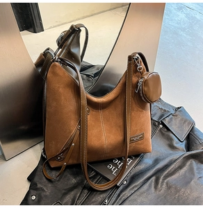 Detail of brown suede tote bag with round coin purse and fashion metal plaque logo