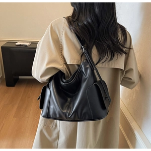 Macro shot of black PU leather shoulder bag featuring spacious side pockets and soft texture