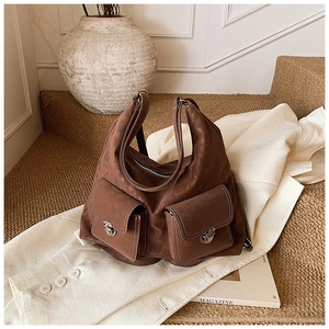 Detail of a brown utility shoulder bag with dual flap pockets and silver metal buckles