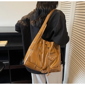 Detail of vintage brown leather bucket bag with metallic rivets and long tassel zipper