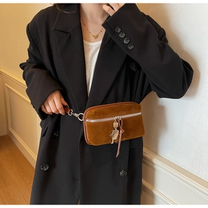 Close-up of caramel suede crossbody bag with silver zipper and metal robot charm detail