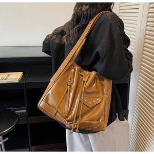 Detail view of a brown vintage bucket bag with metallic zippers and stud accents