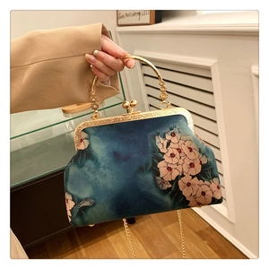 Close-up of vintage floral handbag with gold metal handle and navy blue fabric detail