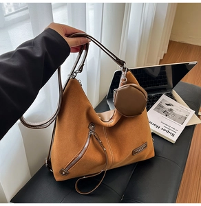 Close-up of brown suede tote bag featuring slanted zipper pocket and round mini coin purse
