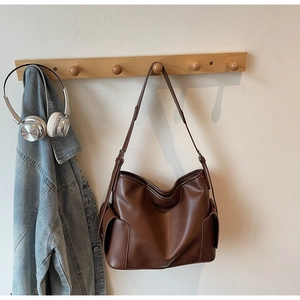 Detail of caramel brown PU leather tote bag showing side pocket and soft texture