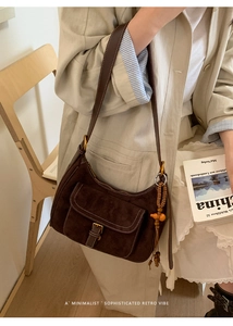 Close-up of retro dark brown matte suede shoulder bag with ethnic beaded charm accessory