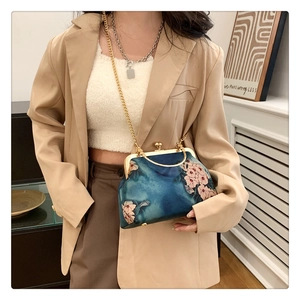 Close-up of vintage floral embroidery and golden metal clasp on navy fabric bag