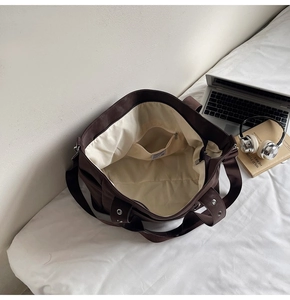 Detail of dark brown tote bag with cream lining, zip pocket and wide shoulder strap