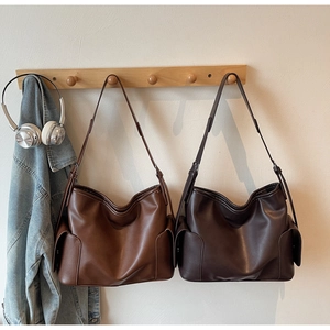 Detail of large brown PU leather tote bag with functional side pockets and adjustable strap