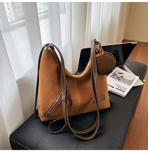 Detail of a brown suede tote bag with white stitching and a small round coin purse