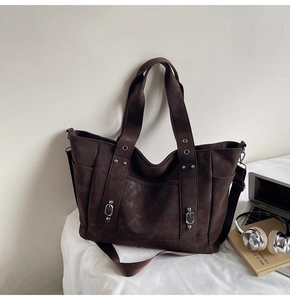 Detail of dark brown suede tote bag featuring metallic rivets and detachable shoulder strap
