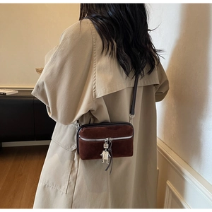 Detailed back view of a vintage dark brown suede crossbody bag with robot pendant charm