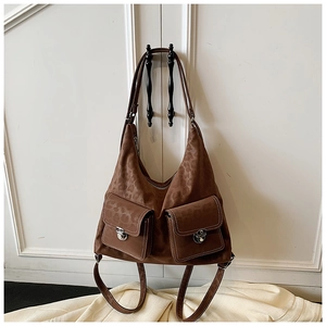 Close-up of brown textured leather bag with dual front pockets and silver buckle hardware